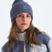 Person wearing a blue knit beanie and a matching fleece jacket on a white background