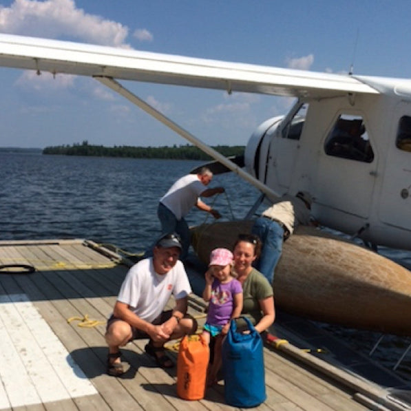 Family with a child by a small airplane on a dock by water