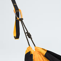 Close-up of a yellow and black hammock with ropes against a light gray background