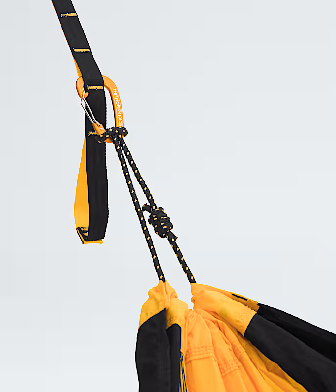 Close-up of a yellow and black hammock with ropes against a light gray background