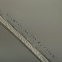 Close-up of a tent with 'Mountain Safety Research' branding on a gray background