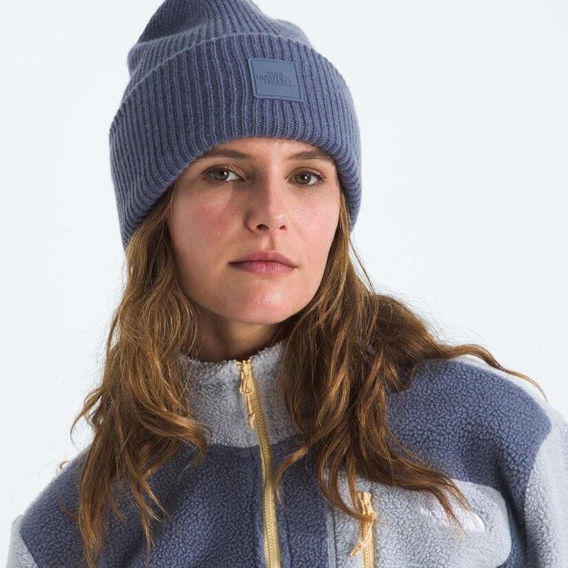 Person wearing a blue knit beanie and a matching fleece jacket on a white background