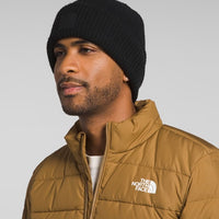 Man wearing a black beanie and brown The North Face jacket on a gray background