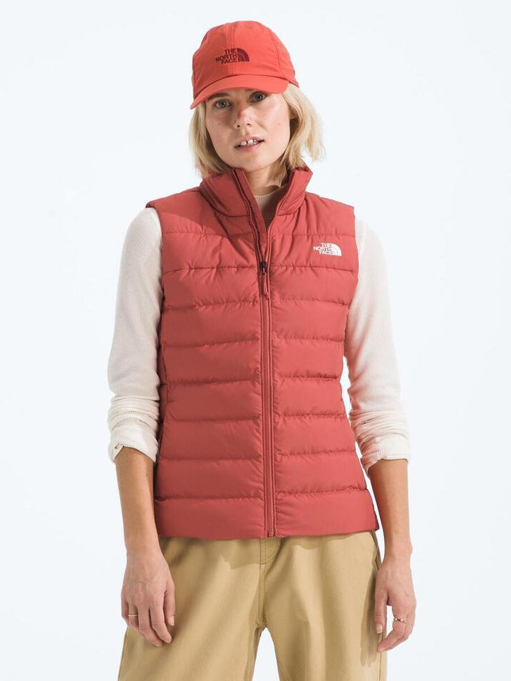 Person wearing a red puffer vest and cap on a white background