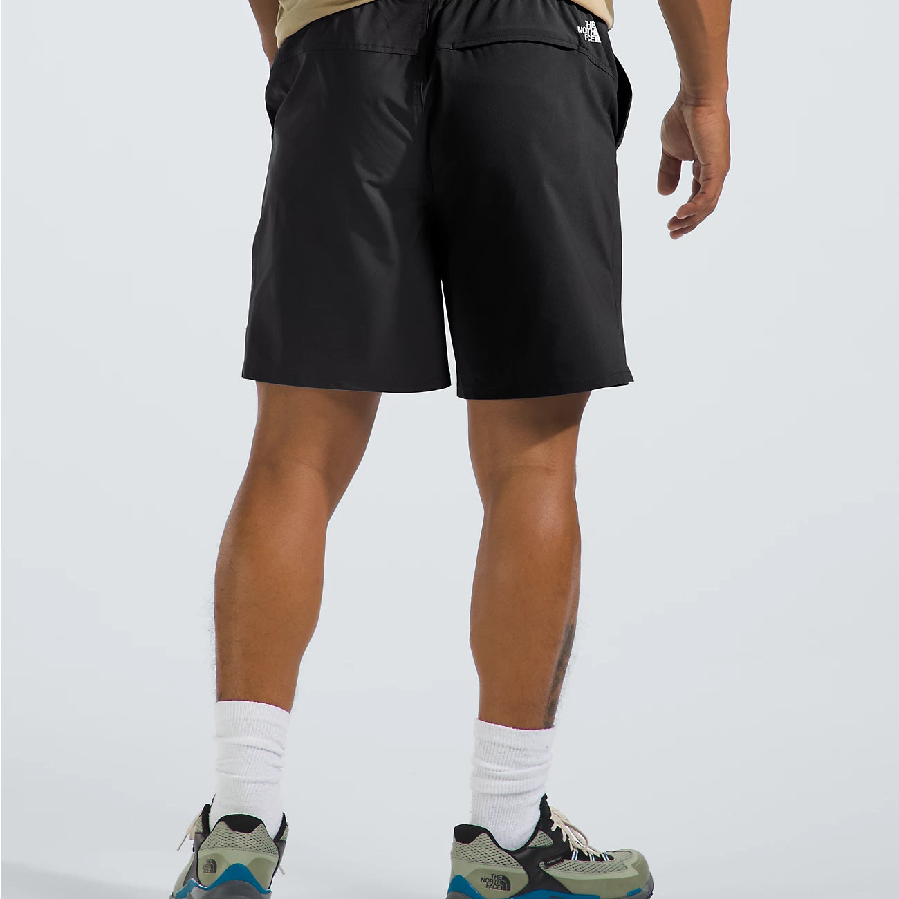 Person wearing black shorts with a brand logo on a light gray background