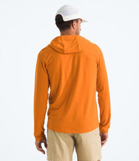 Man wearing an orange hoodie and beige pants on a white background