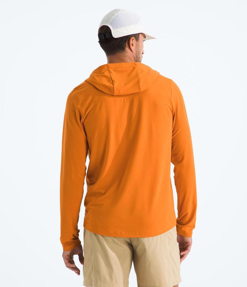 Man wearing an orange hoodie and beige pants on a white background