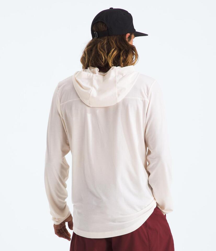 Person wearing a white hoodie and maroon pants with a black cap on a white background
