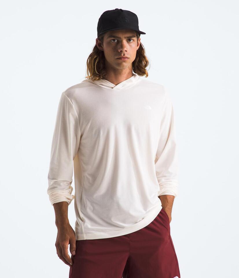 Man wearing a white hoodie and maroon pants on a plain background