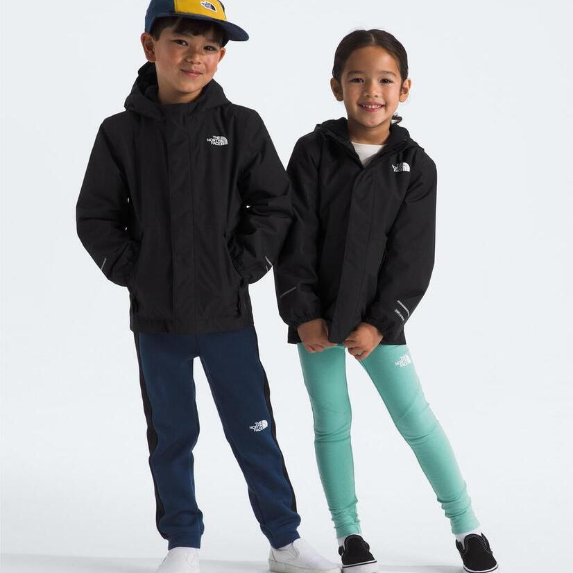 Two children wearing matching black hoodies with a brand logo on a white background