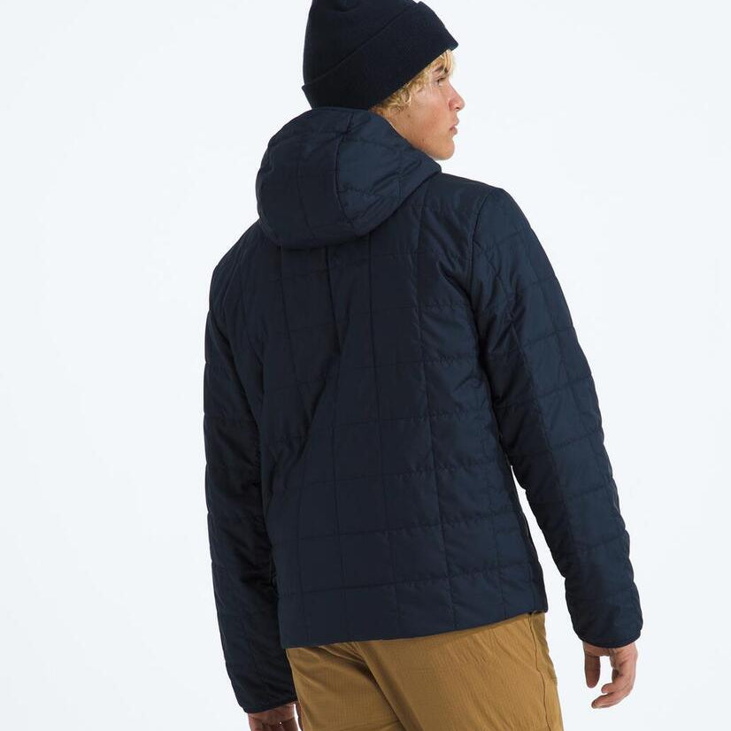 Person wearing a dark blue puffer jacket and black beanie on a white background