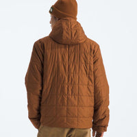 Person wearing a brown puffer jacket and beanie on a white background