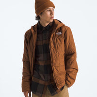 Person wearing a brown jacket and beanie with a visible brand logo on a white background