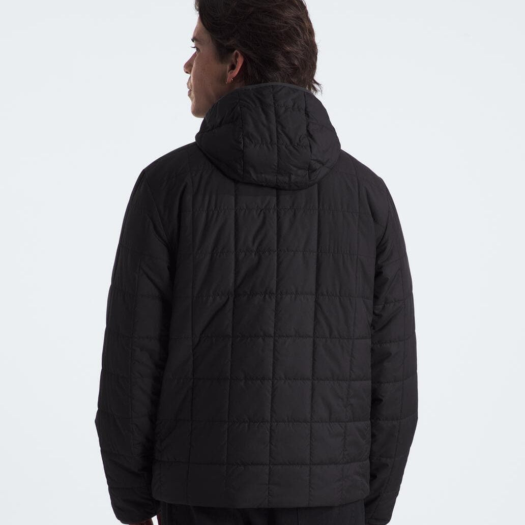 Person wearing a black quilted jacket on a white background