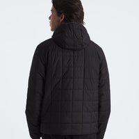 Person wearing a black quilted jacket on a white background