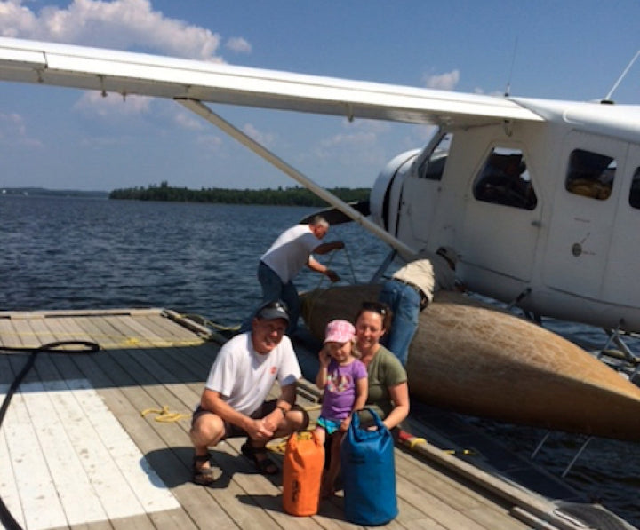 Family with a child by a small airplane on a dock by water